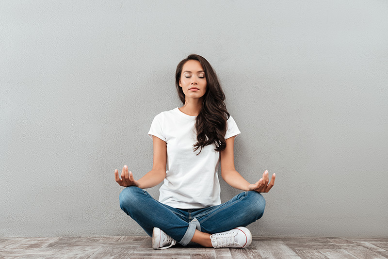 A woman practices coping skills for trauma and meditates in an open space.